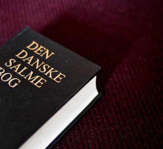 Den danske salmebog på bordeaux baggrund.