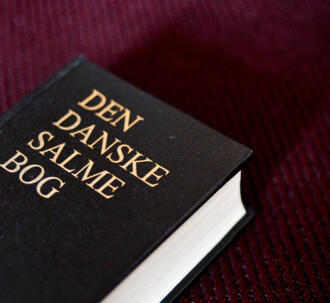 Den danske salmebog på bordeaux baggrund.
