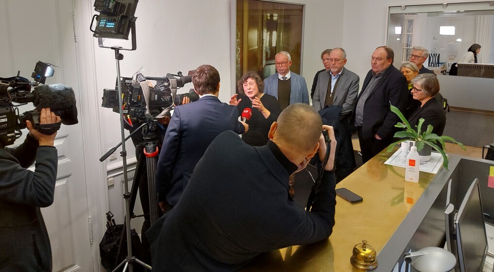 Otte af biskopperne står foran rullende kameraer, mens den ene taler med fremmødte journalister