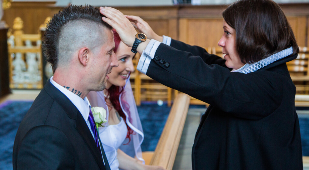 Præst velsigner et brudepar, som knæler foran alteret