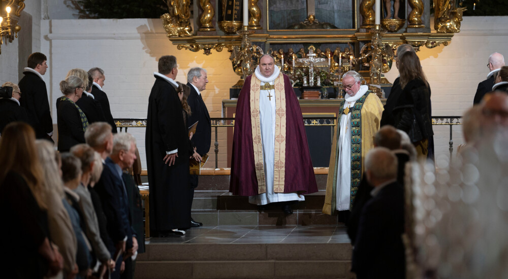 Tilskuere i kirken står op for den nye biskop