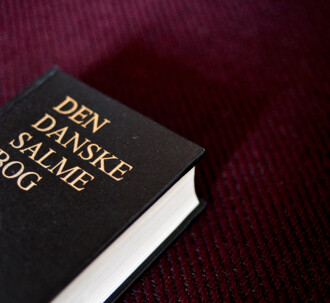 Den danske salmebog på bordeaux baggrund.