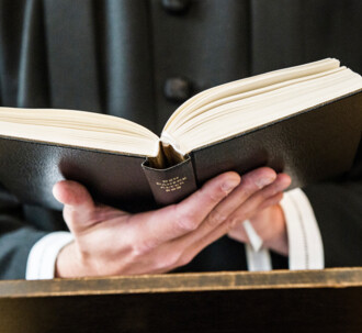 En præst kigger i den danske salmebog.