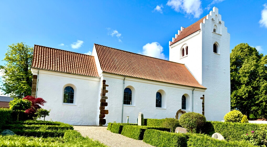Hvid middelalderkirke i solskin